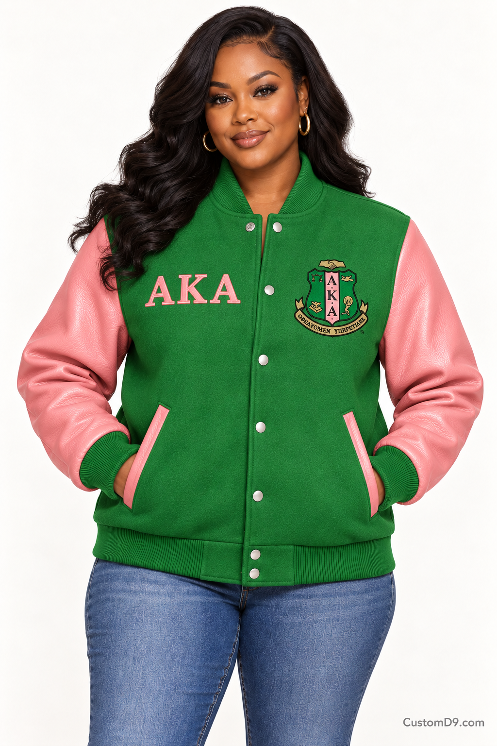 Black woman modeling Alpha Kappa Alpha apple green body and salmon pink sleeve premium varsity jacket, front view; horizontal Greek letters on right chest and crest on left chest.