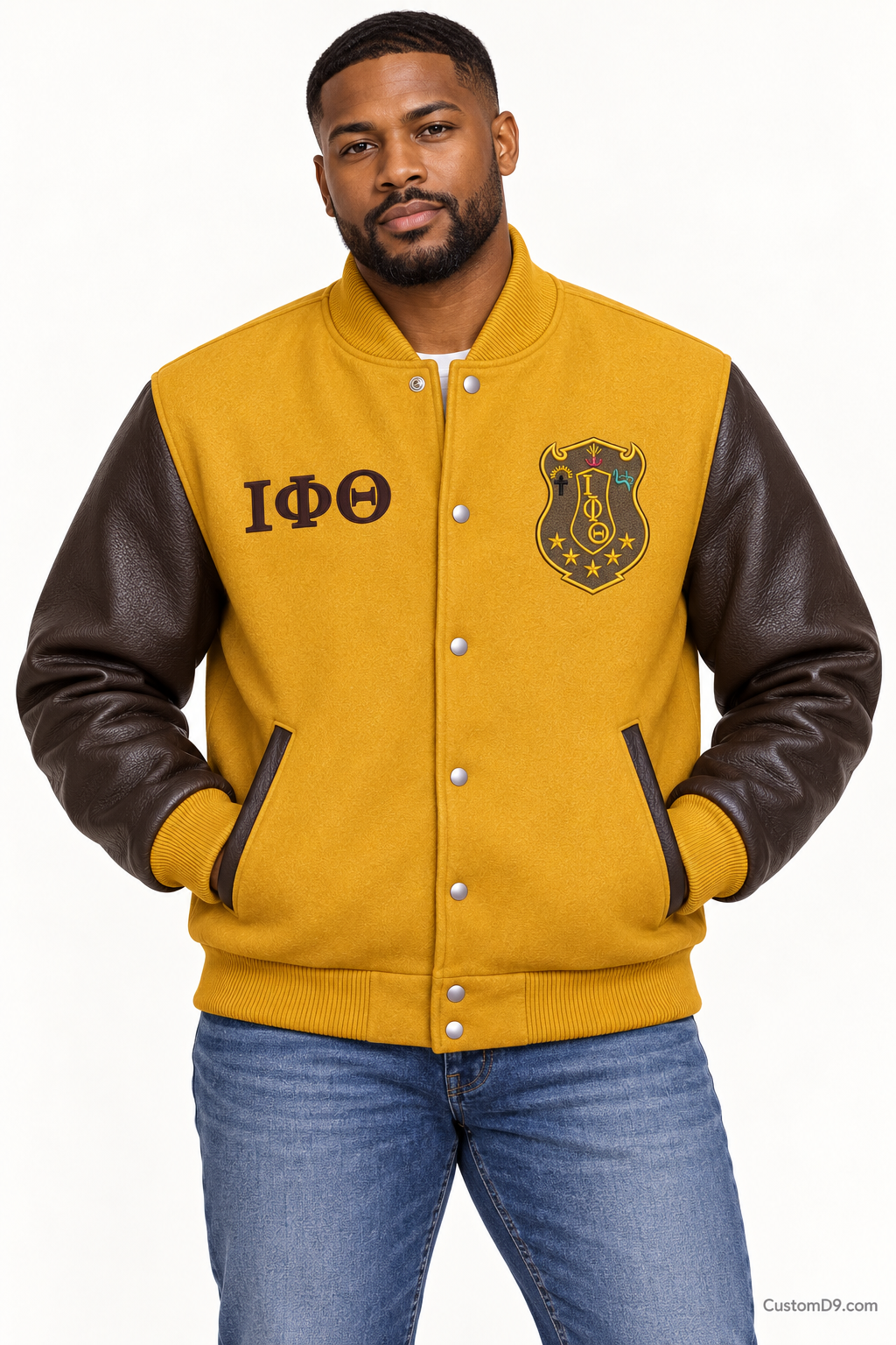 Black man modeling Iota Phi Theta premium contrast varsity jacket with gilded gold body and charcoal brown sleeves, front view.