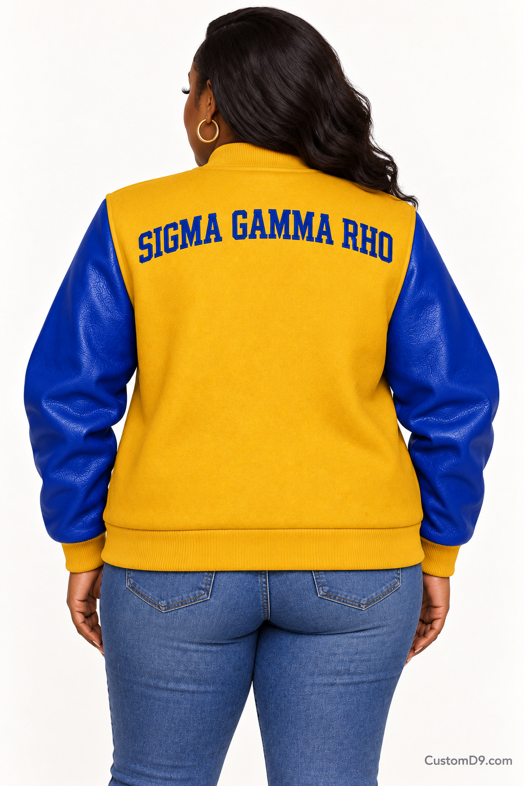 Black woman modeling Sigma Gamma Rho gold body and royal blue sleeve premium varsity jacket, back view; arched organization name across upper back.