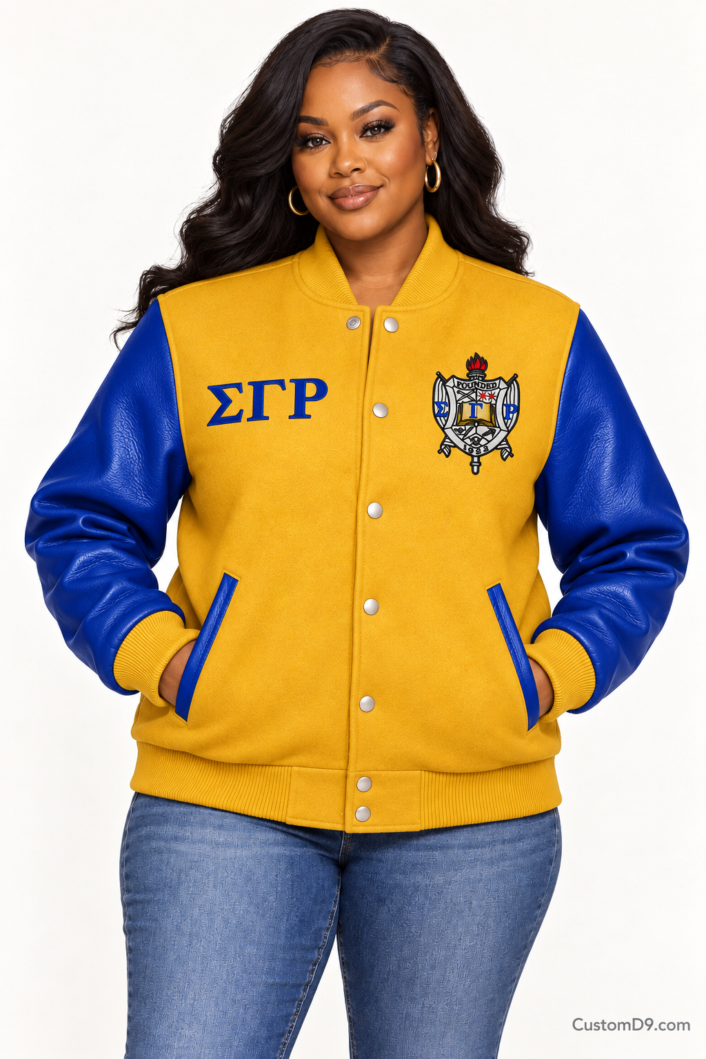 Black woman modeling Sigma Gamma Rho gold body and royal blue sleeve premium varsity jacket, front view; horizontal Greek letters on right chest and crest on left chest.