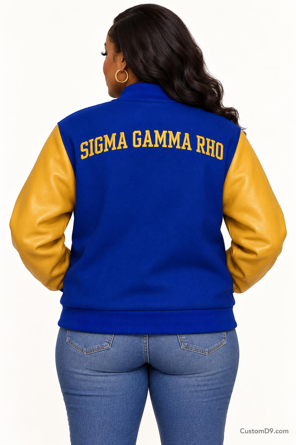 Black woman modeling Sigma Gamma Rho royal blue body and gold sleeve premium varsity jacket, back view; arched organization name across upper back.