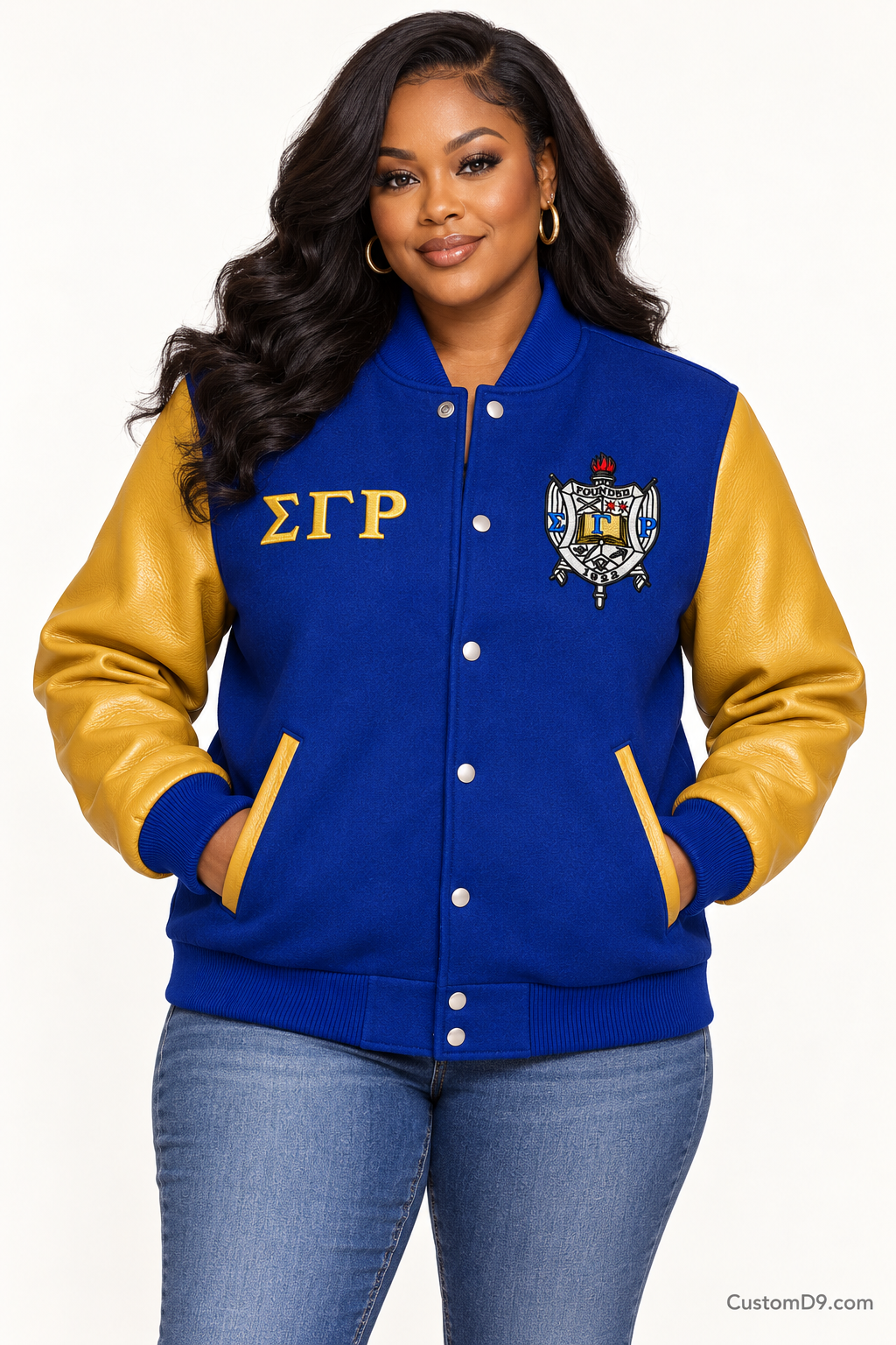 Black woman modeling Sigma Gamma Rho royal blue body and gold sleeve premium varsity jacket, front view; horizontal Greek letters on right chest and crest on left chest.