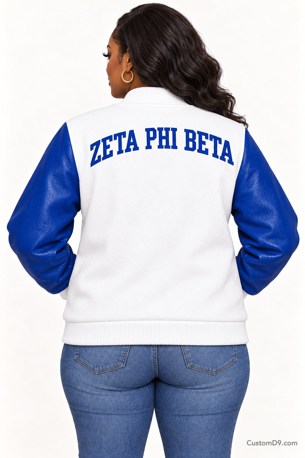 Black woman modeling Zeta Phi Beta white body and royal blue sleeve premium varsity jacket, back view; arched organization name across upper back.