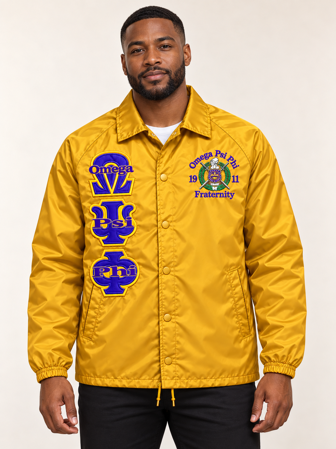 Black male model wearing a gold Omega Psi Phi custom embroidered coach line jacket with purple letters and crest