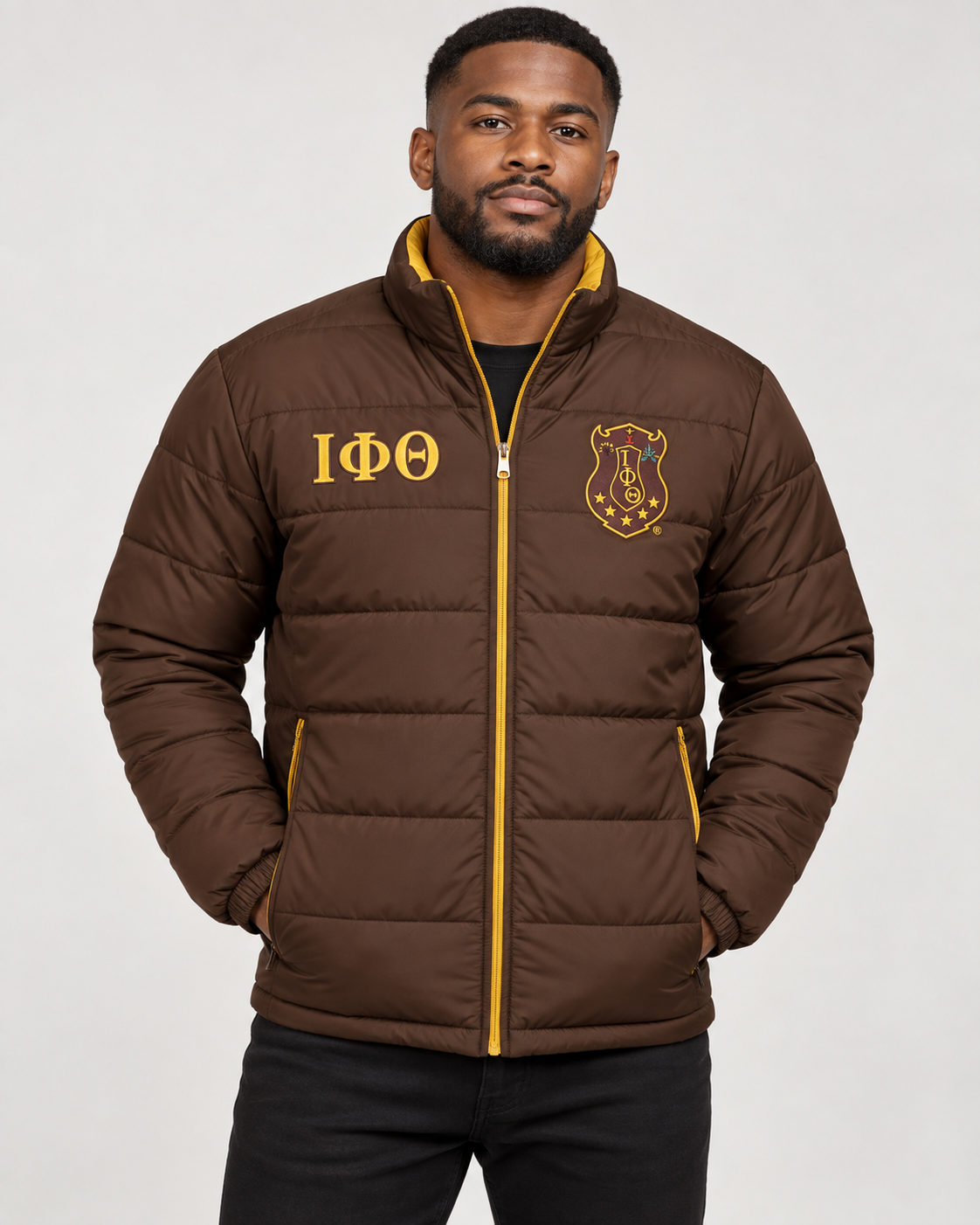 Iota Phi Theta brown puffer jacket with gold contrast and embroidery on male model
